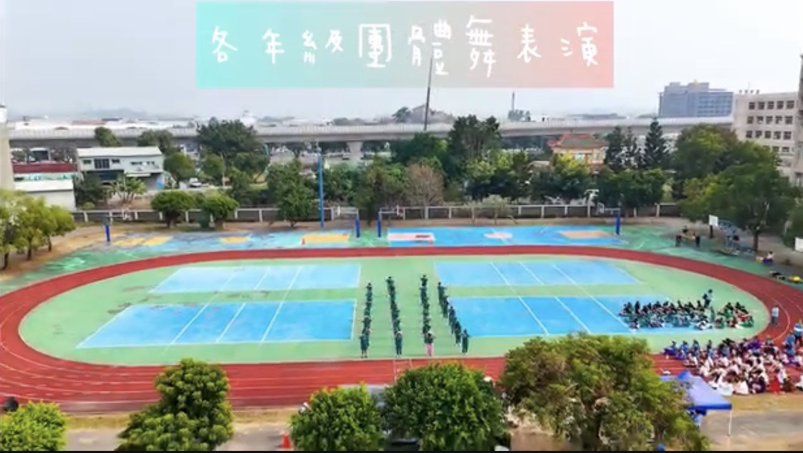 校園運動場全景，呈現團體表演隊形與周圍觀眾